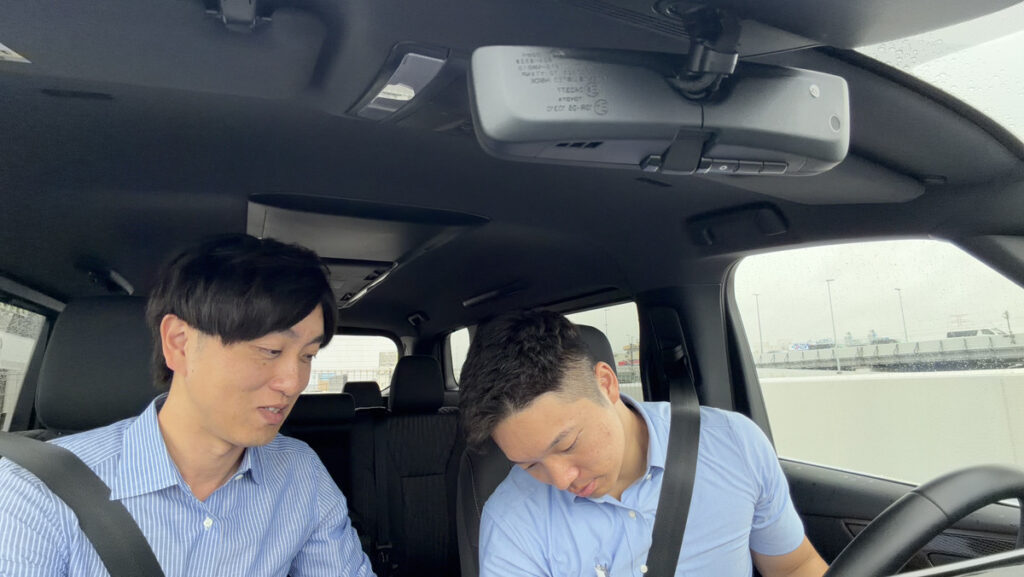 指導員が社員に運転のポイントを説明している様子